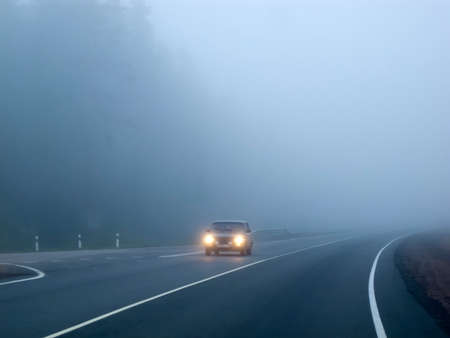 Cars in the fog. Bad weather and dangerous automobile traffic on the road. Light vehicles in fog.の写真素材