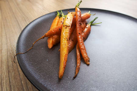 Fried carrots with green herbs in a pan, close up.の写真素材