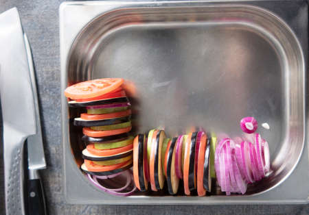 preparing a vegetarian dish from vegetables in your home kitchen. thinly sliced vegetables baked and...