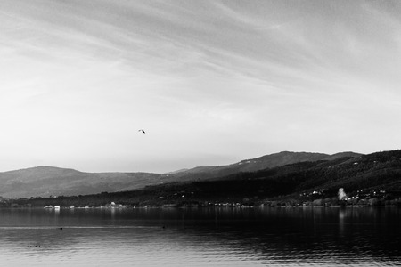Beautiful view of Trasimeno lake (Umbria, Italy), with hills and sky reflecting on waterの写真素材