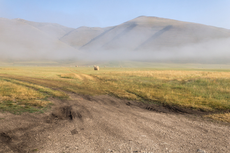 View of Castelluccio di Norcia (Umbria, Italy) upland at morning, with haybales and mistの写真素材