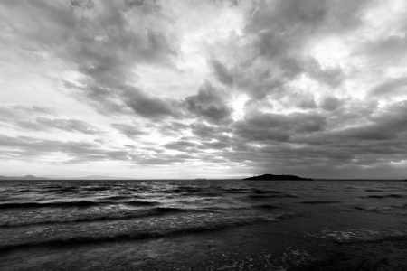 A lake at dusk, with majestic cloudscape, dark water and an island in the backgroundの写真素材