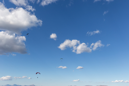 Some para gliders flying against a deep, blue sky, with big whitの写真素材
