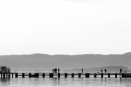 A pier on a lake with several people on it doing various socialの写真素材