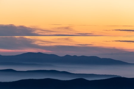Beautifully colored sky at dusk, with mountains layers and mist between them