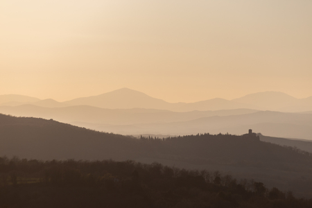 Beautiful view of Tuscany hills at sunset, with mist and warm colorsの写真素材