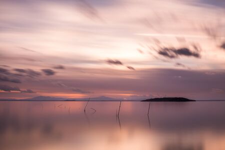 Beautiful long exposure view of Trasimeno Lake (Umbria, Italy), with still water and warm coloured sky.の写真素材