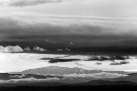 View of dark clouds at sunset, over and below a mountain