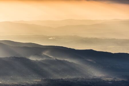 Sunrays coming over a valley in Umbria (Italy) with beautiful golden hours colors.の写真素材