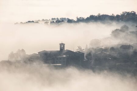 Surreal view of of a little town in Umbria (Italy) almost completely hidden by fog.の写真素材