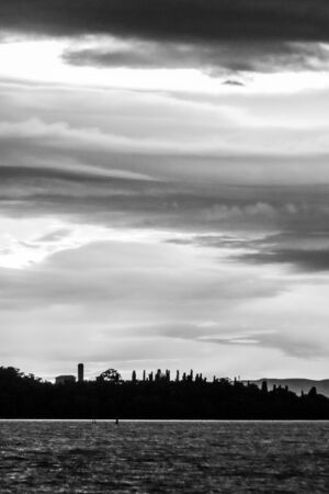 View of Isola Maggiore on Trasimeno lake at dusk, beneath a dramatic, beautiful skyの写真素材