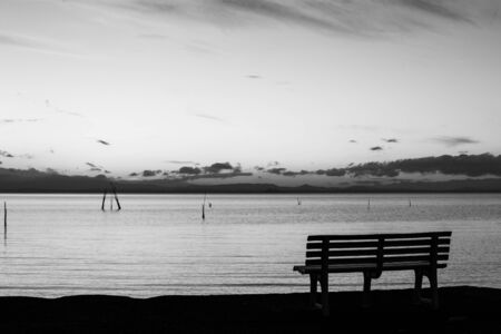 Dusk at Trasimeno lake (Umbria, Italy), with a parking bench on the foreground.の写真素材