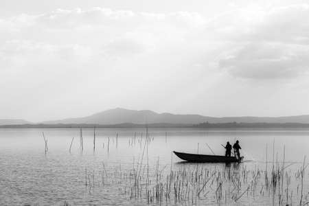 Two men on a little boat fishing in a lakeの写真素材