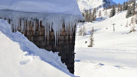 cabin with icicles and snow and skiing lift in background
