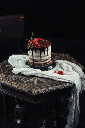 Chocolate cake with red currants on a tableの写真素材