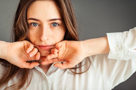 Young girl in a white shirt on a gray background. French woman in white blouse against a background...