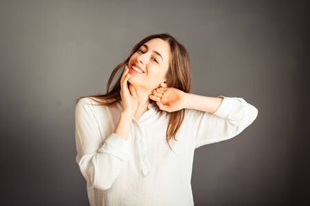 Young girl in a white shirt on a gray background. French woman in white blouse against a background...