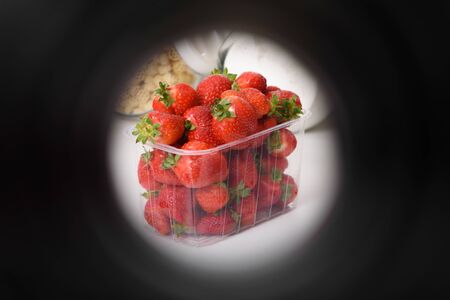 good organic strawberries in a plastic box on a white background in a dark stroke. delivery of organic products. packaging of organic strawberries.の写真素材