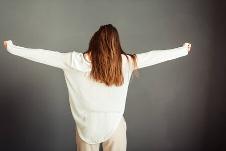 Young girl in a white shirt on a gray background. French woman in white blouse on a background of gray walls. Without retouching and makeup.の写真素材