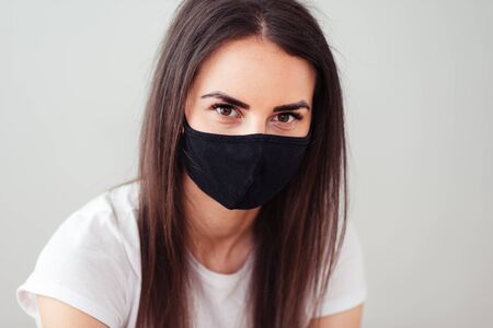 Portrait of a young woman wearing a black facial mask. Dust protection against viruses. Coronavirus pandemic time. A woman is looking at the camera. Crime.の写真素材