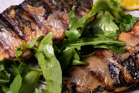 grilled chicken fillet closeup with arugula and lemon on a platter, healthy nutrition