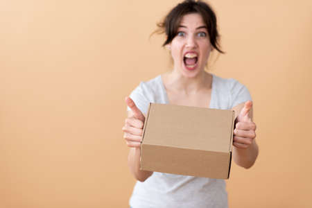 A girl sits at a table and laughs showing a finger at the screen with a stack of corton boxes on white izolate backgraundの写真素材