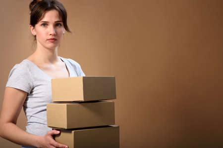 A girl sits at a table and laughs showing a finger at the screen with a stack of corton boxes on white izolate backgraundの写真素材