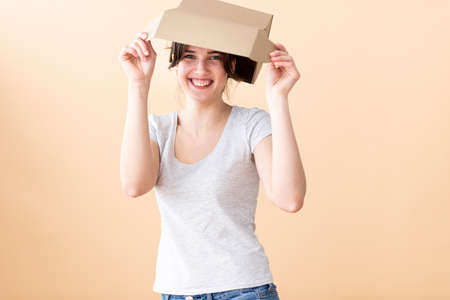 A girl sits at a table and laughs showing a finger at the screen with a stack of corton boxes on white izolate backgraundの写真素材