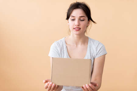 The girl looks at the cardboard box with a smile and interest. Surpriseの写真素材