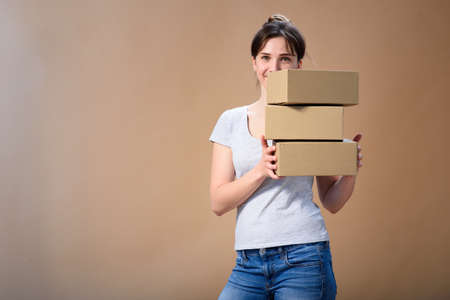 European girl peeking out from behind boxes and smiling cutely. Advertising spaceの写真素材