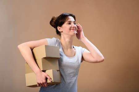 laughing girl delivering brown boxes on beige backgroundの写真素材
