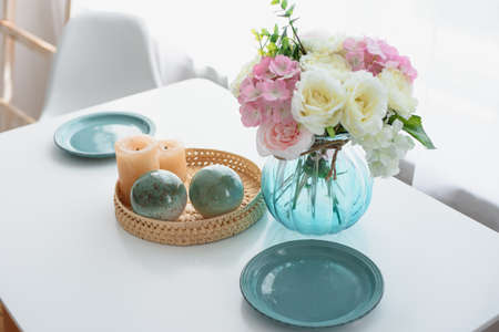 Kitchen white table. Serving on a white table. Green plates. Flowers on the table. Candles.