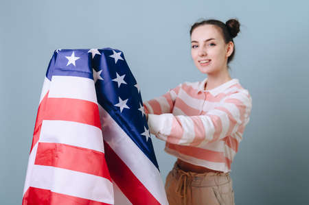 Volunteer girl with an american flag on an isolated blue background, a cute girl in a striped...
