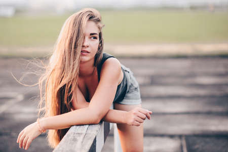 Portrait of a young girl with long hair on a summer evening, resting after a workout. The girl chills in nature.の写真素材