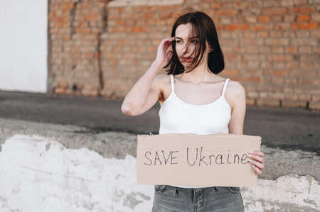 The girl holds a sign about the request to stop the war. Save Ukraine. War Ukraine vs Russiaの写真素材