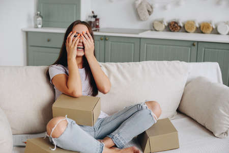 The girl Caucasian sits in the kitchen on the sofa and closes her eyes with her hands hysterically...