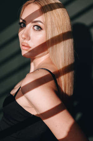 Close-up portrait of a hard light blonde against a dark background. The concept of self-confidence....