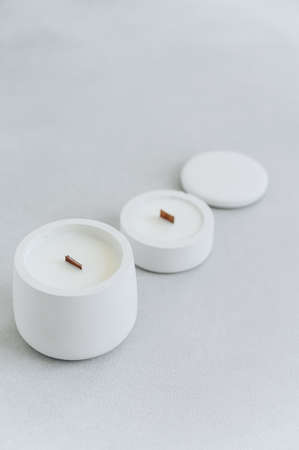 Group of Candles of various sizes in Gypsum candlesticks on Gray Background. Convex concrete vessel with lid on concrete background. Chiaroscuro. minimalism.の写真素材