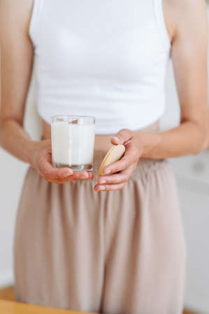 Woman in Light Clothes Holds Soy Candle in her Hands in Glass and Wooden Lid. Hold in Hands Decor Element. Scented Candle. Place for label.の写真素材