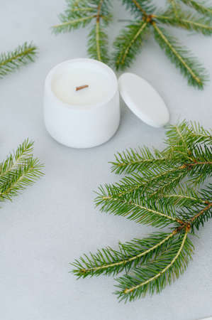 White Candle in Plaster Pot with Free Space for Label. sideview. Fir Branches on Light Table. copyspace.の写真素材
