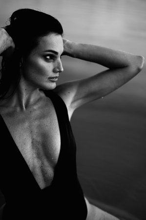 Black White Portrait of Young Woman with Muscular Body in Piece Swimsuit Looking Away. Hands at Head. Girl with Troubled Eye.の写真素材