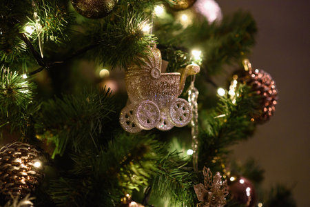 Christmas Toy in Form of Stroller on Green Christmas tree Close-up Among Christmas Tree Lights. Christmas card, screensaver, backgroundの写真素材
