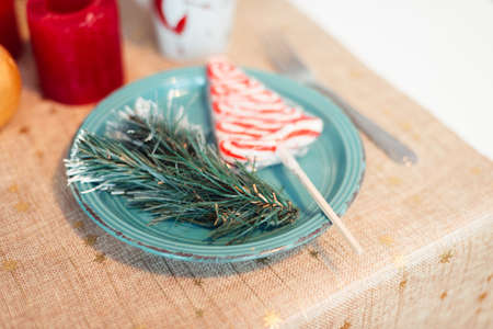 Turquoise Plate on Table with Christmas Tree Branch and Lollipop. christmas concept. Festive Table...