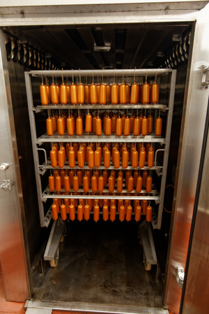 Meat sausages hanging in factory smokehouseの写真素材