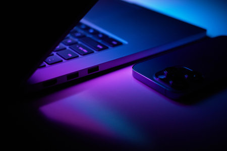 Laptop with smartphone. Neon dark light.の写真素材
