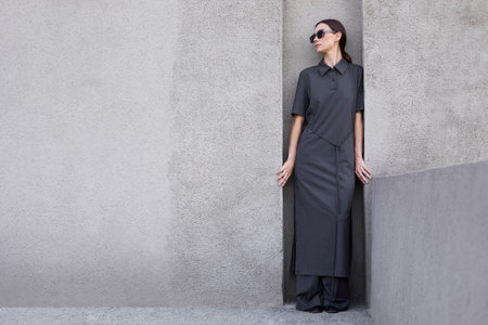 High fashion portrait of young elegant Asian woman in long gray dress outdoor. Sunglasses, minimalist asian fashion, elegant look, modern concrete urban backgroundの写真素材