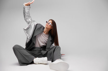 Fashion asian female model in silver down jacket and gray suit. White sneakers, sunglasses. Asian fashionの写真素材
