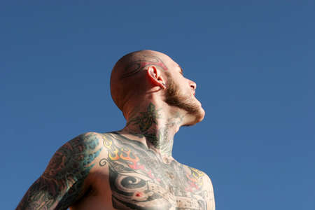 Man with tattoos against blue skyの写真素材