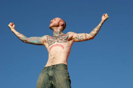 Man with tattoos against blue skyの写真素材