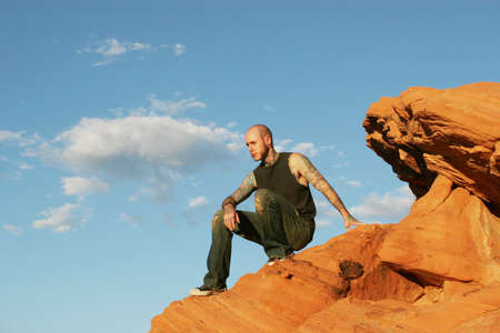 Tattoo man sitting on red rocksの写真素材